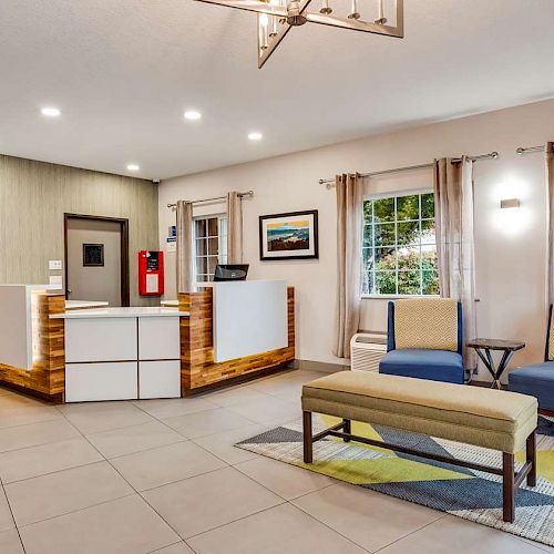 This image shows a hotel lobby with a front desk, seating area, and decor including pictures and curtains. The lighting is warm and inviting.